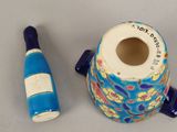 a blue vase and a bottle of wine next to each other