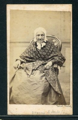 une vieille photo d'une femme assise sur une chaise, un foulard sur la tête