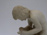 a small statue of a boy kneeling on the ground