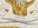 a close up of a white and yellow scarf with a picture of a drum