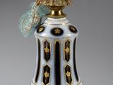 un vase blanc et doré surmonté d'un oiseau