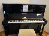 un piano dans un coin de la pièce, avec un tabouret