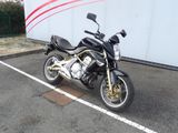 a black motorcycle parked in a parking lot next to a wall