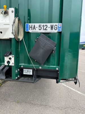 a green container that has a black trash can inside of it