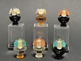 four glass vases with different colored flowers in them on a gray surface