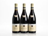 trois bouteilles de vin rouge posées l'une à côté de l'autre sur une surface blanche