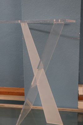 une table claire avec un plateau en verre, posée à même le sol