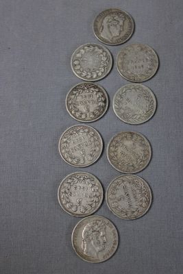 Plusieurs pièces d'argent sont alignées sur une surface grise