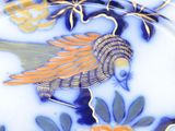 a blue and yellow plate with a bird and flowers on it