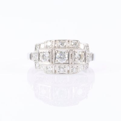 a close up of a diamond and white gold ring on a white surface