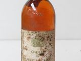 an old bottle of wine sitting on top of a white table