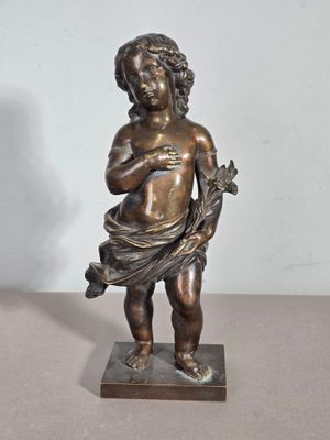 statue en bronze représentant un garçon tenant un oiseau, posée sur un socle en marbre