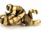 an antique ivory figurine of a man wrestling a tiger