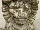 a stone statue of a lion with a flower on its head
