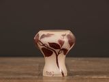 a small vase sitting on a wooden table with a black background