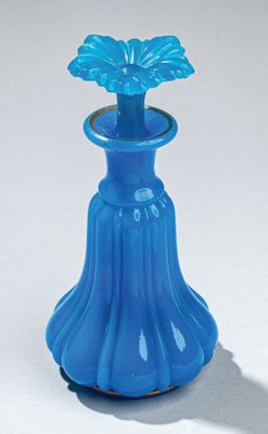 un vase bleu contenant une fleur, posé sur une surface blanche