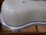 a white porcelain dog bone with blue trim on a wooden crate