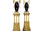 une paire de vases dorés et bleus sur des socles, sur fond blanc