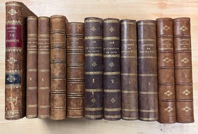 several old books are lined up on a shelf on a wooden surface