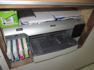 a printer sitting on top of a cabinet next to a pile of papers
