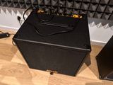 a black amp sitting on the floor next to a speaker