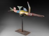 une photo représentant une sculpture d'oiseau colorée posée sur un socle en métal