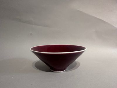 a red and white bowl sitting on a white surface
