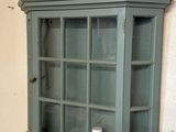a shelf with a glass door and a vase on the wall