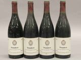quatre bouteilles de vin sont alignées sur une surface blanche
