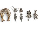 three silver and gold animal charms and a pair of earrings on a white surface