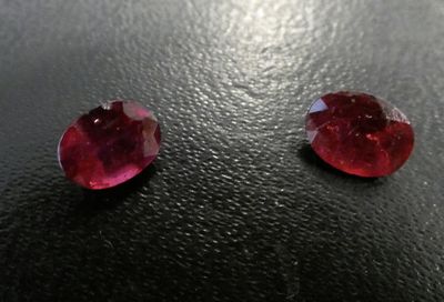 a pair of red sapphires sitting on top of a black surface
