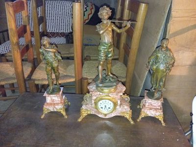 quatre statues représentant des personnes posées sur une table sur laquelle se trouve une horloge