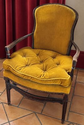 une chaise jaune placée devant un rideau rouge