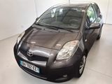 une Toyota Yaris noire garée dans une pièce blanche