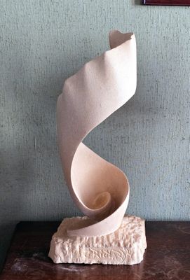 une sculpture blanche posée sur une table en bois, avec un tableau accroché au mur derrière elle