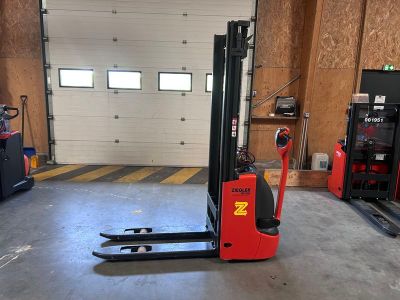 un chariot élévateur rouge dans un garage avec deux autres chariots élévateurs