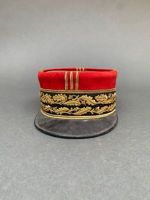 un gros plan sur un chapeau rouge orné de passementerie dorée