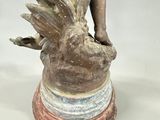 a statue of a boy holding a bird on top of a vase