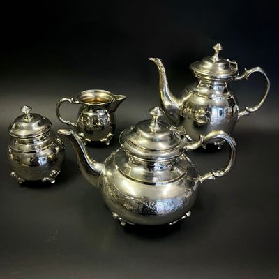trois théières en argent et deux tasses en argent posées sur une table