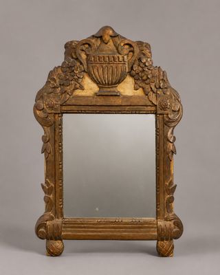 un miroir richement sculpté surmonté d'un vase