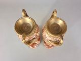 pair of pink and gold vases on a white surface
