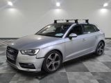 the silver audi is parked on a checkered floor in a garage