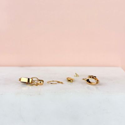 a pair of gold hoop earrings on a marble surface