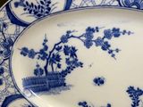 a blue and white plate with a tree and flowers on it
