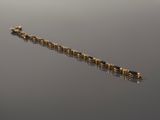 an image of a gold bracelet with black stones on a reflective surface