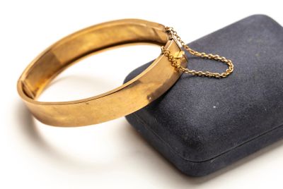 une bague en or munie d'une chaîne, posée sur un coffret noir