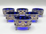 six blue glass bowls with silver decorations on them on a white surface