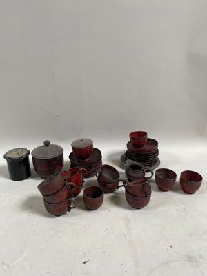 il y a beaucoup de tasses et de soucoupes rouges sur la table