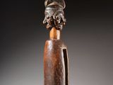 une sculpture en bois représentant une femme coiffée d'une coiffe