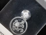 a silver coin with a diamond on it in a clear box